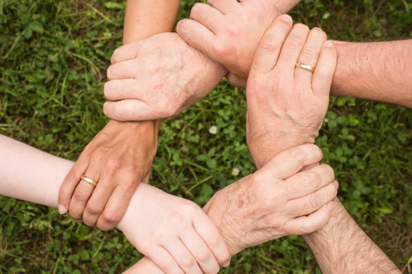 La familia funcionando como un equipo, se sujetan las manos entre sí formando un círculo