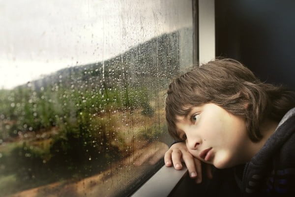Traumas, duelos y adaptación al cambio, niño triste mirando por la ventana